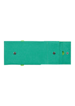 The PACKAGE by GOOD GOODS ISSEY MIYAKE is a green tri-fold mini wallet with two snap buttons and a circular cutout—stylish and perfect as a gift.