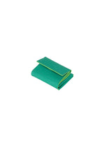 A green rectangular cleaning sponge by GOOD GOODS ISSEY MIYAKE, called PACKAGE, folded with slightly rounded edges like a tri-fold mini wallet, displayed on a white background.