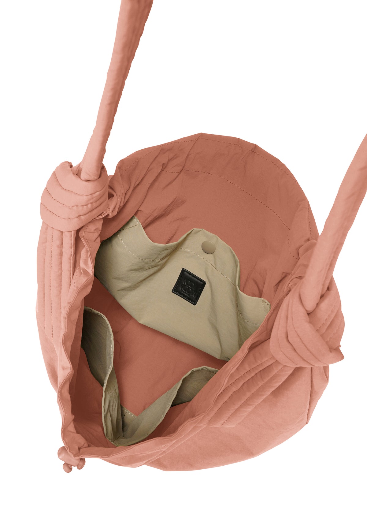 A top view of the pink FUWA FUWA fabric shoulder bag by GOOD GOODS ISSEY MIYAKE, featuring knotted straps inspired by Japanese zero-waste design. The beige-lined interior includes a buttoned pocket and a small black label. view 5 of 7