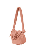 The FUWA FUWA bag by GOOD GOODS ISSEY MIYAKE is a soft, quilted shoulder bag in muted pink, featuring a knotted strap and ruched front inspired by Japanese noragi style, crafted with zero-waste design and shown on a plain white background.