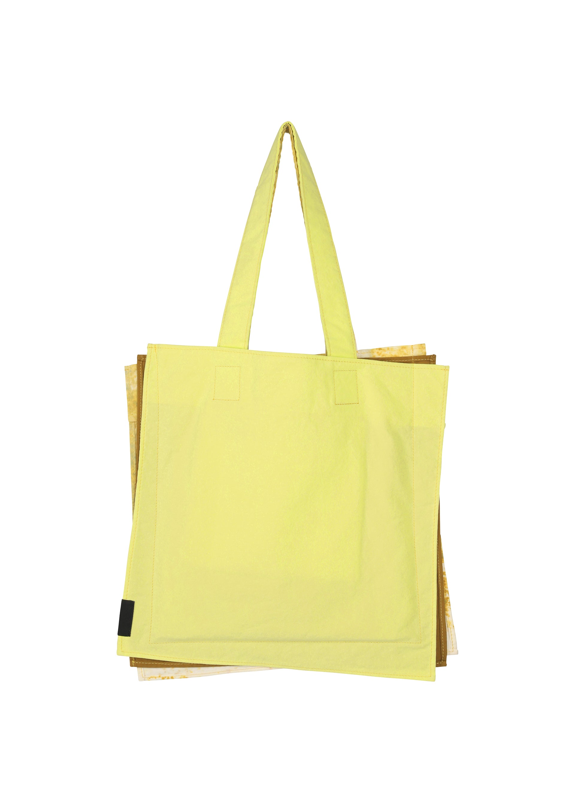 Zoomed view A large yellow IROGAMI SALT DYE tote bag by GOOD GOODS ISSEY MIYAKE, featuring Shio-zome dyeing and two shoulder straps, is shown on a plain white background with part of a brown or gold bag partially visible behind it.