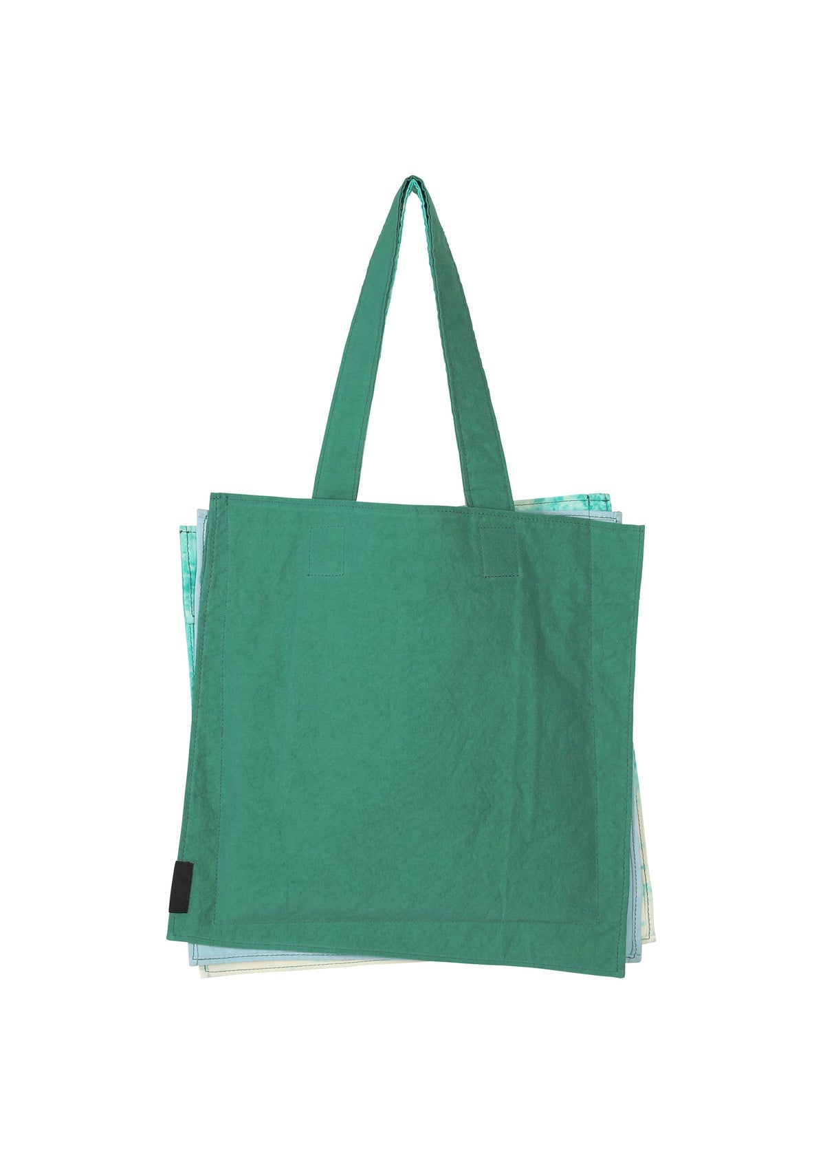 A green reusable tote bag from GOOD GOODS ISSEY MIYAKE’s IROGAMI SALT DYE series with two handles sits slightly open, revealing folded bags inside, against a white background. view 6 of 10