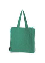 A green reusable tote bag from GOOD GOODS ISSEY MIYAKE’s IROGAMI SALT DYE series with two handles sits slightly open, revealing folded bags inside, against a white background.