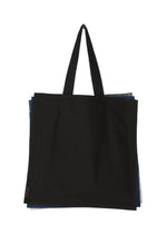 A large black IROGAMI SALT DYE tote bag by GOOD GOODS ISSEY MIYAKE with two handles, photographed on a white background. Edges of layered, salt-dyed patterned fabric peek out from behind the main bag.