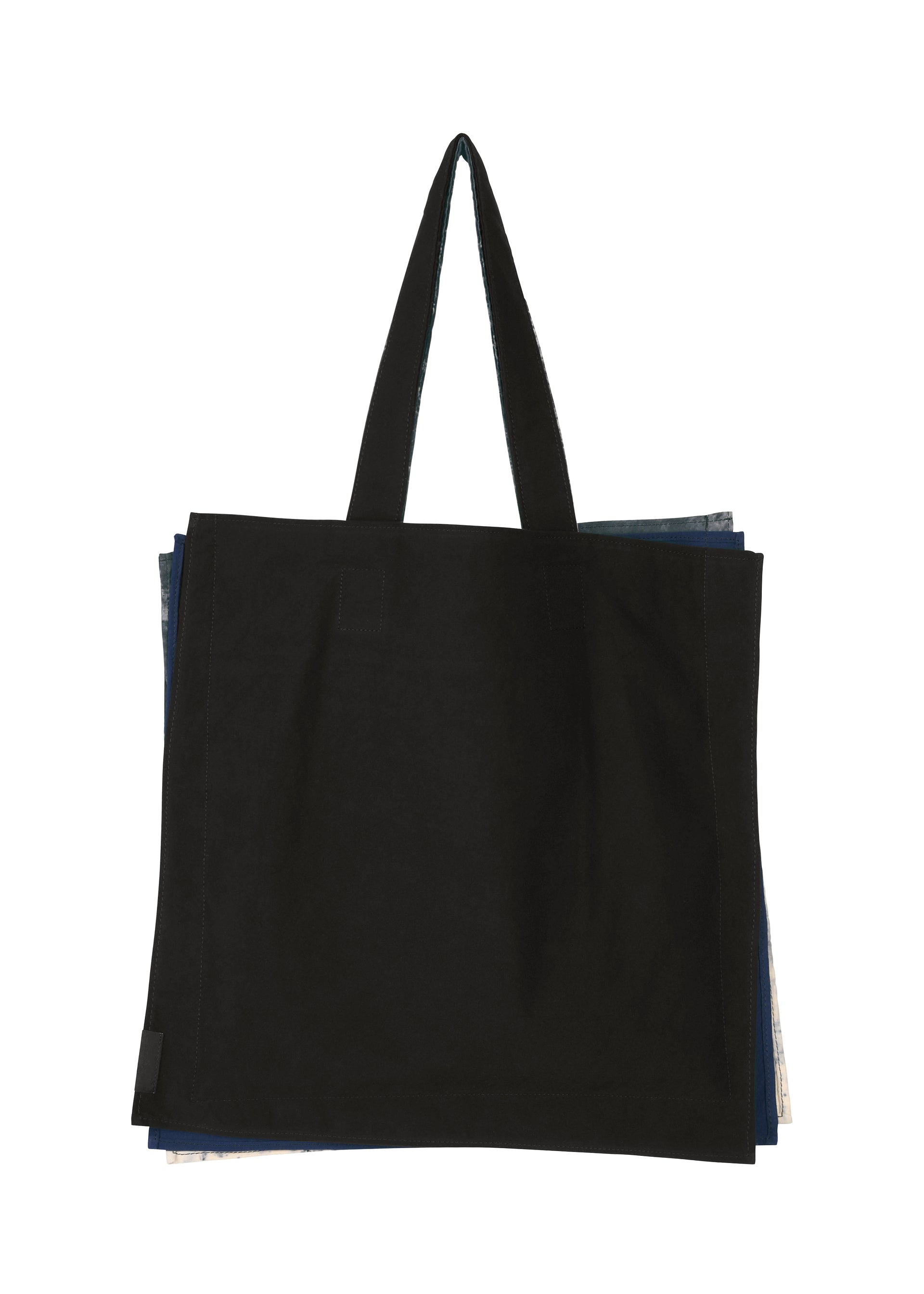 Zoomed view A large black IROGAMI SALT DYE tote bag by GOOD GOODS ISSEY MIYAKE with two handles, photographed on a white background. Edges of layered, salt-dyed patterned fabric peek out from behind the main bag.
