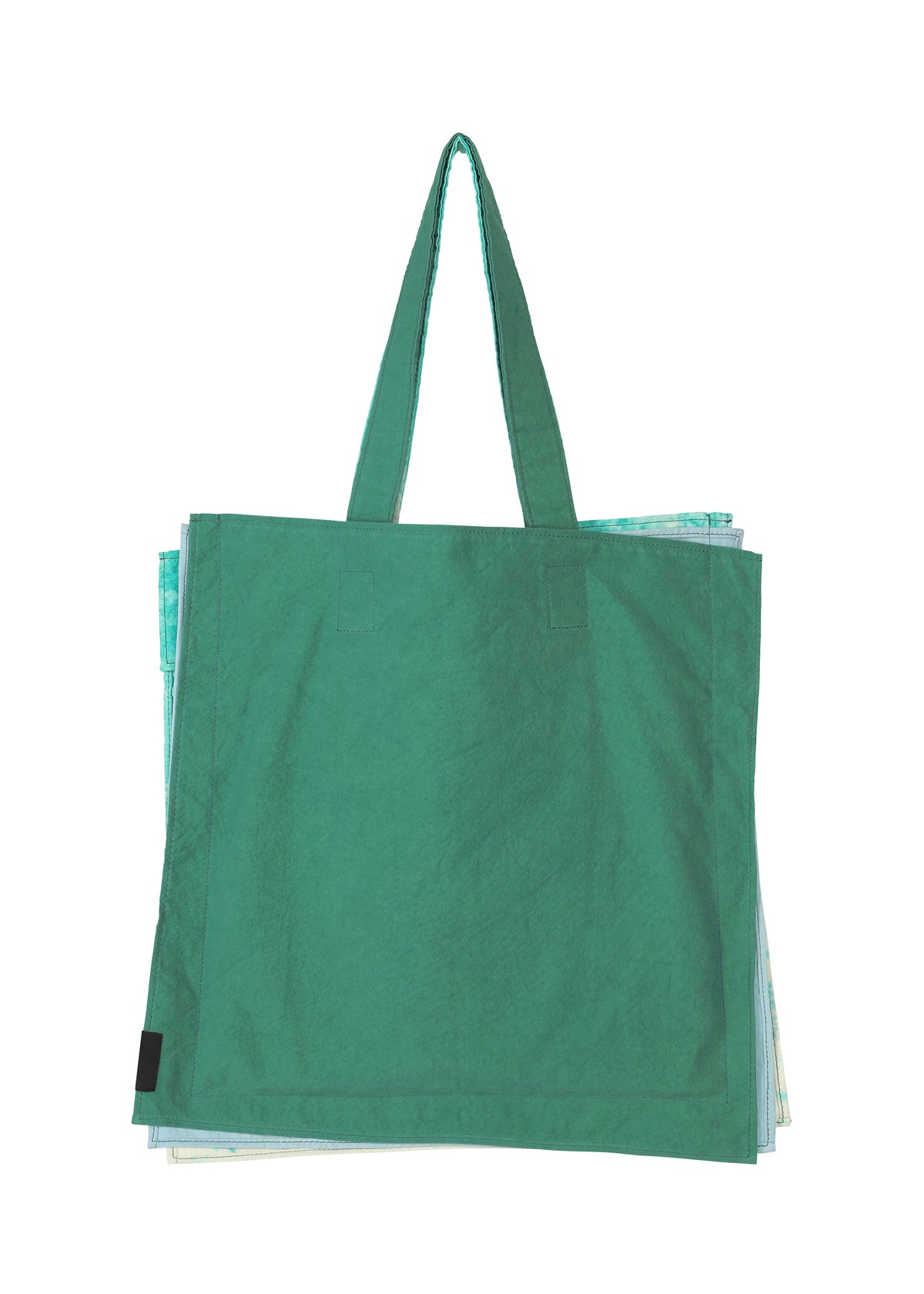 A large green IROGAMI SALT DYE tote bag by GOOD GOODS ISSEY MIYAKE, with long handles and made using the salt-dyeing technique, is shown against a white background with light blue and white bags partially visible behind it. view 6 of 10