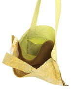 The IROGAMI SALT DYE by GOOD GOODS ISSEY MIYAKE is a yellow tote bag with an open top, brown interior pocket, single wide strap, and slightly textured material crafted with the unique Shio-zome (salt-dyeing) technique.