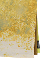 A close-up of overlapping IROGAMI SALT DYE fabric napkins by GOOD GOODS ISSEY MIYAKE, featuring a yellow and white marbled salt-dye pattern, neat edge stitching, and a small black CODY FOSTER tag on one napkin.