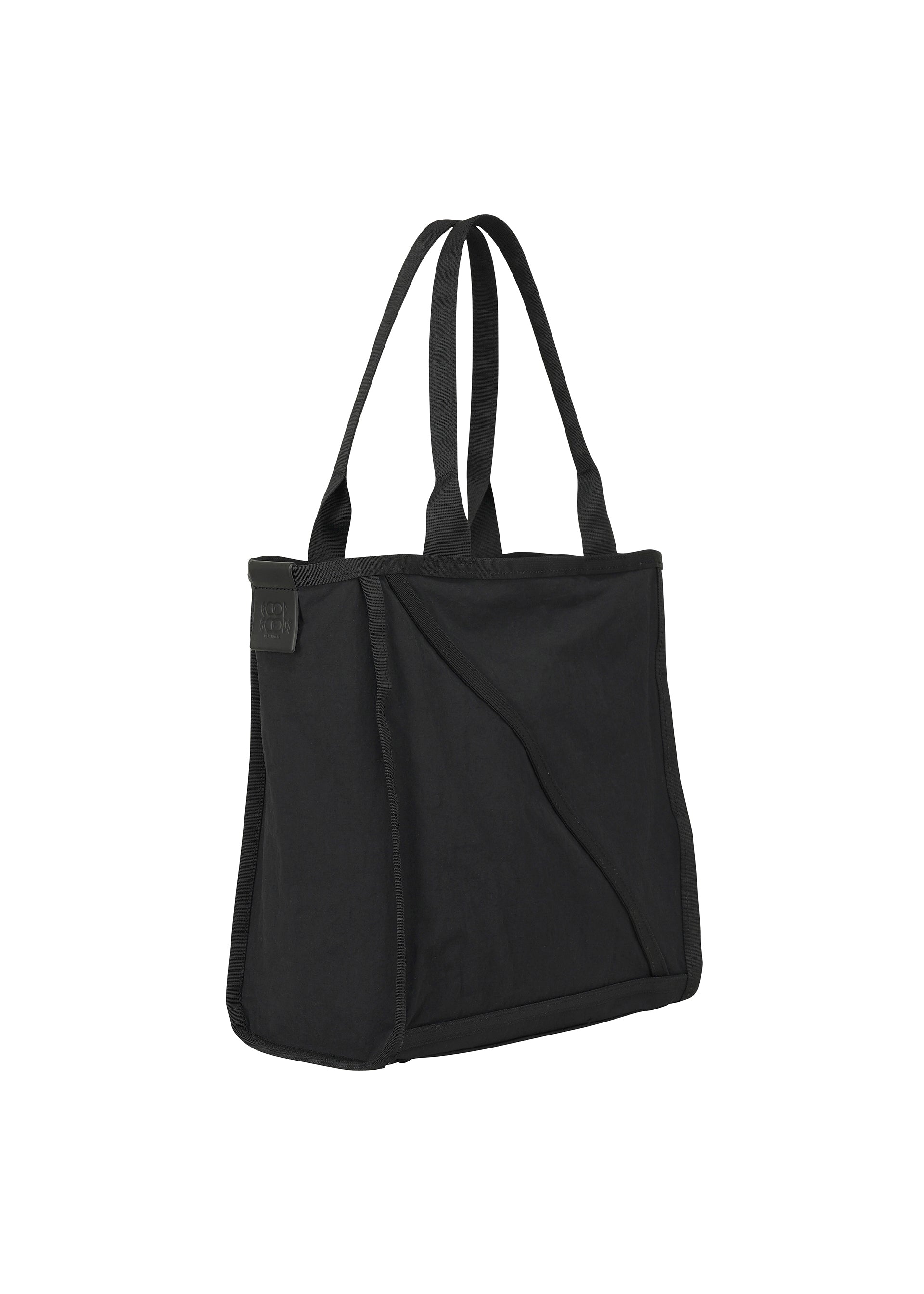 Zoomed view The WAKU by GOOD GOODS ISSEY MIYAKE is a black fabric tote bag with two long handles, wide gussets for extra space, and an exterior diagonal pocket, shown on a white background.