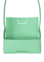 The BOX by GOOD GOODS ISSEY MIYAKE is a mint green leather convertible shoulder bag with a minimalist, box-inspired shape, an open top, slim strap, and subtle embossed front logo.