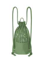 The MOKKO KNAPSACK by GOOD GOODS ISSEY MIYAKE is a green, washable knit bag with a woven lattice upper, solid lower section, adjustable shoulder straps, and knotted ends.