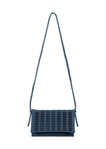 The MOKKO FLAP POUCH by GOOD GOODS ISSEY MIYAKE is a dark blue, washable shoulder bag with a long strap and rectangular flap featuring a grid-like cut-out pattern—both stylish and practical. - MARINE BLUE （no.79）