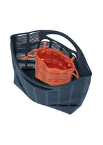 The MOKKO S.C. POCKET by GOOD GOODS ISSEY MIYAKE features a blue washable, wavy open-weave bag holding a smaller orange knit drawstring pouch—ideal for Spring Summer 2026 and shown on a white background.