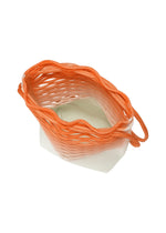 The MOKKO NET GRADATION basket by GOOD GOODS ISSEY MIYAKE features orange woven sides fading to white at its base, a wavy irregular edge, and an open top. Its lightweight design is reminiscent of a knit bag. Shown on a white background.