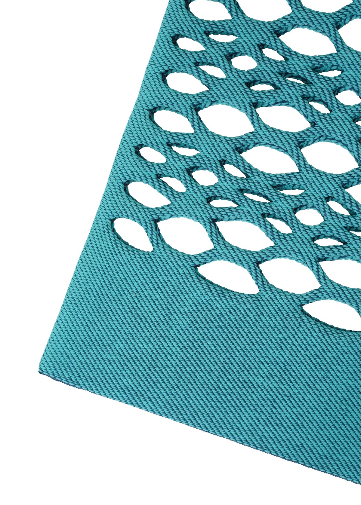 A close-up of the blue textured fabric from the MOKKO BASKET by GOOD GOODS ISSEY MIYAKE, featuring an array of oval-shaped cutouts that create a geometric pattern against a white background. view 4 of 6
