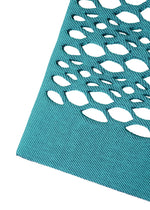 A close-up of the blue textured fabric from the MOKKO BASKET by GOOD GOODS ISSEY MIYAKE, featuring an array of oval-shaped cutouts that create a geometric pattern against a white background.