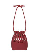The MOKKO BASKET by GOOD GOODS ISSEY MIYAKE is a small, red knit bag with a honeycomb-patterned cutout upper, solid bottom, and bow-tied drawstring top. Washable and stylish, it captures the charm of classic basket bags. - DARK BORDEAUX×CRIMSON RED （no.82）
