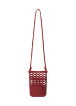 The MOKKO BASKET by GOOD GOODS ISSEY MIYAKE is a small red shoulder bag with a long strap and open honeycomb-style cutouts on the front, reminiscent of a chic knit pochette. - DARK BORDEAUX×CRIMSON RED （no.82）