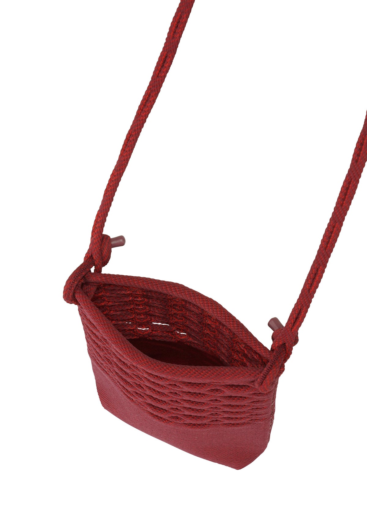 The MOKKO BASKET by GOOD GOODS ISSEY MIYAKE, a small red woven knit pochette with a long strap and open top, is photographed from above on a white background. view 4 of 8
