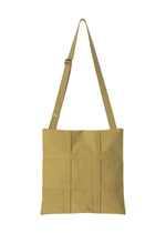 The GRID shoulder bag by GOOD GOODS ISSEY MIYAKE features a tan square design with an adjustable strap and a stitched grid pattern on the front, shown here against a white background. - DARK YELLOW （no.53）