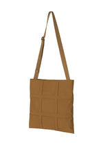 The GRID shoulder bag by GOOD GOODS ISSEY MIYAKE features a brown, flat-rectangular design with a front grid pattern and an adjustable strap, shown against a white background.