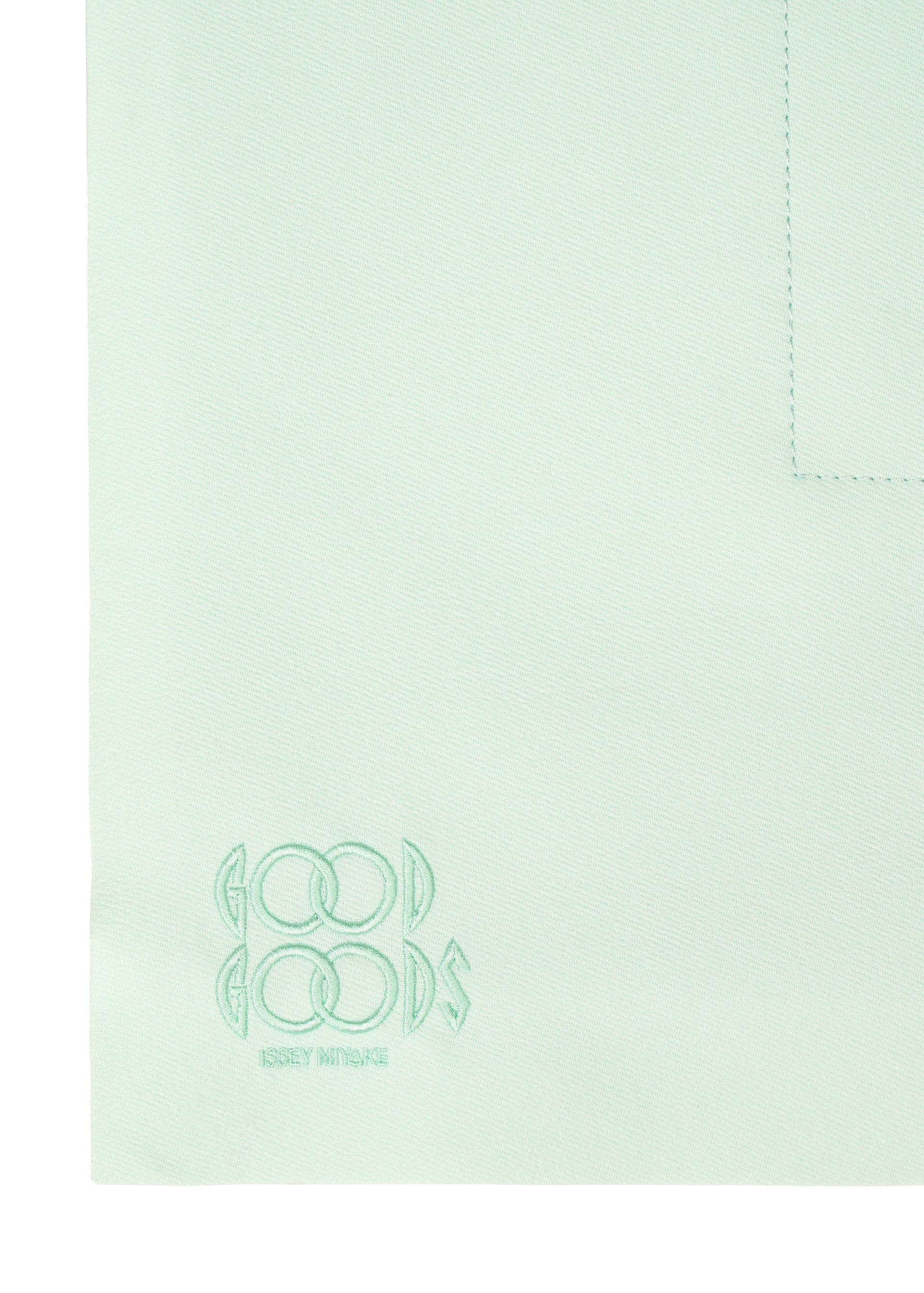 Zoomed view A close-up of ROLL by GOOD GOODS ISSEY MIYAKE shows light mint green fabric with an elegant sheen, visible seam, and embroidered logo text in one corner.