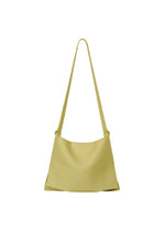 The ROLL by GOOD GOODS ISSEY MIYAKE is a minimalist light yellow shoulder bag with a long strap, featuring a simple, unadorned design. Lightweight and elegant, it's shown on a white background. - LIGHT KHAKI (no.66)