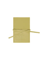 The GOOD GOODS ISSEY MIYAKE ROLL apron in beige or light yellow is shown laid flat on a white background, featuring a neck loop, two front pockets, and extended waist ties.