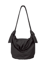 Introducing the FUWA FUWA shoulder bag by GOOD GOODS ISSEY MIYAKE: a black fabric bag featuring a generous, ruched body with pleated sides and a single thick strap, secured with large decorative knots on each side. Inspired by traditional Japanese aesthetics and zero-waste design principles, this bag offers a soft, casual appearance.