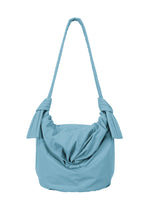 Introducing the FUWA FUWA shoulder bag by GOOD GOODS ISSEY MIYAKE: a light blue, fabric accessory featuring a knotted design on each side of the strap and a gathered, pouch-like silhouette. Inspired by traditional Japanese aesthetics, its soft, subtly textured material stands out against a clean white background. - LIGHT BLUE （no.71）
