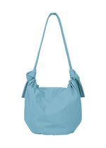 The FUWA FUWA shoulder bag from GOOD GOODS ISSEY MIYAKE features a soft, slouchy shape in light blue fabric. Inspired by traditional Japanese design, it showcases two decorative knots at the handle’s base and a long strap for comfortable over-the-shoulder wear.
