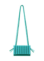 The MOKKO BI-COLOR by GOOD GOODS ISSEY MIYAKE is a turquoise, rectangular shoulder bag with a long strap and perforated front flap. Featuring side ties and a washable design, this stylish tote is shown against a plain white background.