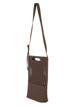 The MOKKO MONO GRIP by GOOD GOODS ISSEY MIYAKE is a brown tote bag featuring a striking cutout grid pattern on the front and a long, adjustable shoulder strap for comfortable carrying. Designed with style and functionality in mind, it also includes an oval hand grip near the top, offering versatile carrying options—making it an ideal business bag or everyday accessory.