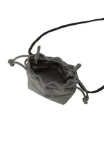 The MOKKO POCKET BI-COLOR by GOOD GOODS ISSEY MIYAKE is a small gray fabric mini bag with a drawstring closure and a long black strap, shown open and empty from above.