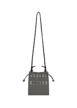 The MOKKO POCKET BI-COLOR by GOOD GOODS ISSEY MIYAKE is a small, rectangular gray mini bag with a long black strap, horizontal cutout details near the top, and adjustable side drawstrings for a chic shoulder pouch style.