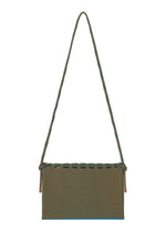 The MOKKO WALE by GOOD GOODS ISSEY MIYAKE is a rectangular shoulder bag with blue and brown stripes, a long twisted strap, knotted top detail, and a minimalist design.