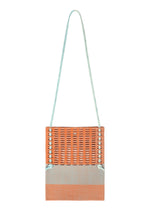 The MOKKO KNOT by GOOD GOODS ISSEY MIYAKE is a rectangular orange knit shoulder bag with a long light blue strap and blue accents, featuring a subtle MOKKO slit pattern, shown against a white background. - WARM ORANGE MIX （no.34）