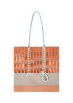 The MOKKO KNOT bag by GOOD GOODS ISSEY MIYAKE is a rectangular knit tote with orange and beige panels, light blue handles, and front decorative knots—perfect for adding a playful accent to your everyday outfits. - WARM ORANGE MIX （no.34）