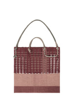 The MOKKO KNOT by GOOD GOODS ISSEY MIYAKE is a square tote bag with a maroon and beige woven design, two rope handles of different lengths, and an open grid-like weave at the top, shown against a white background.