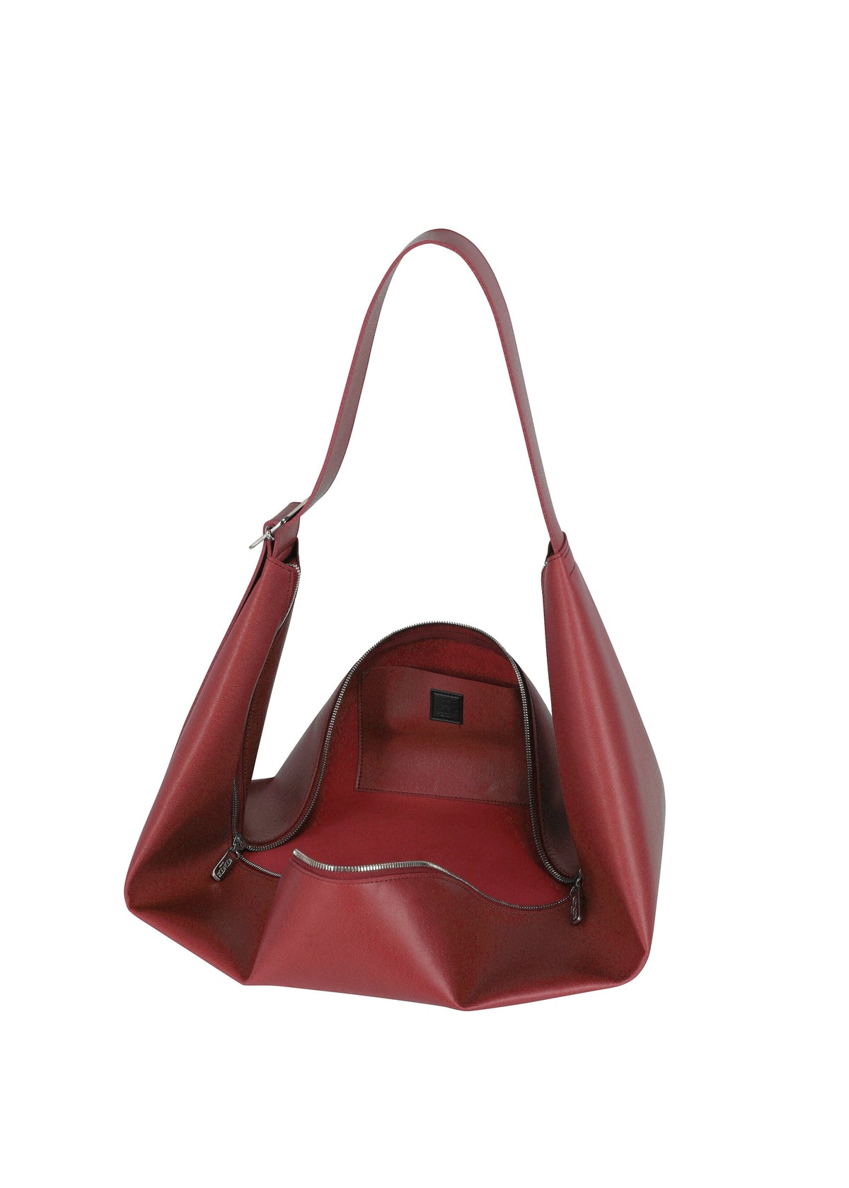 The LEAF by GOOD GOODS ISSEY MIYAKE is a red leather shoulder bag with a wide strap, suede-like lining, zip pocket, and smooth, modern angular design. view 5 of 9