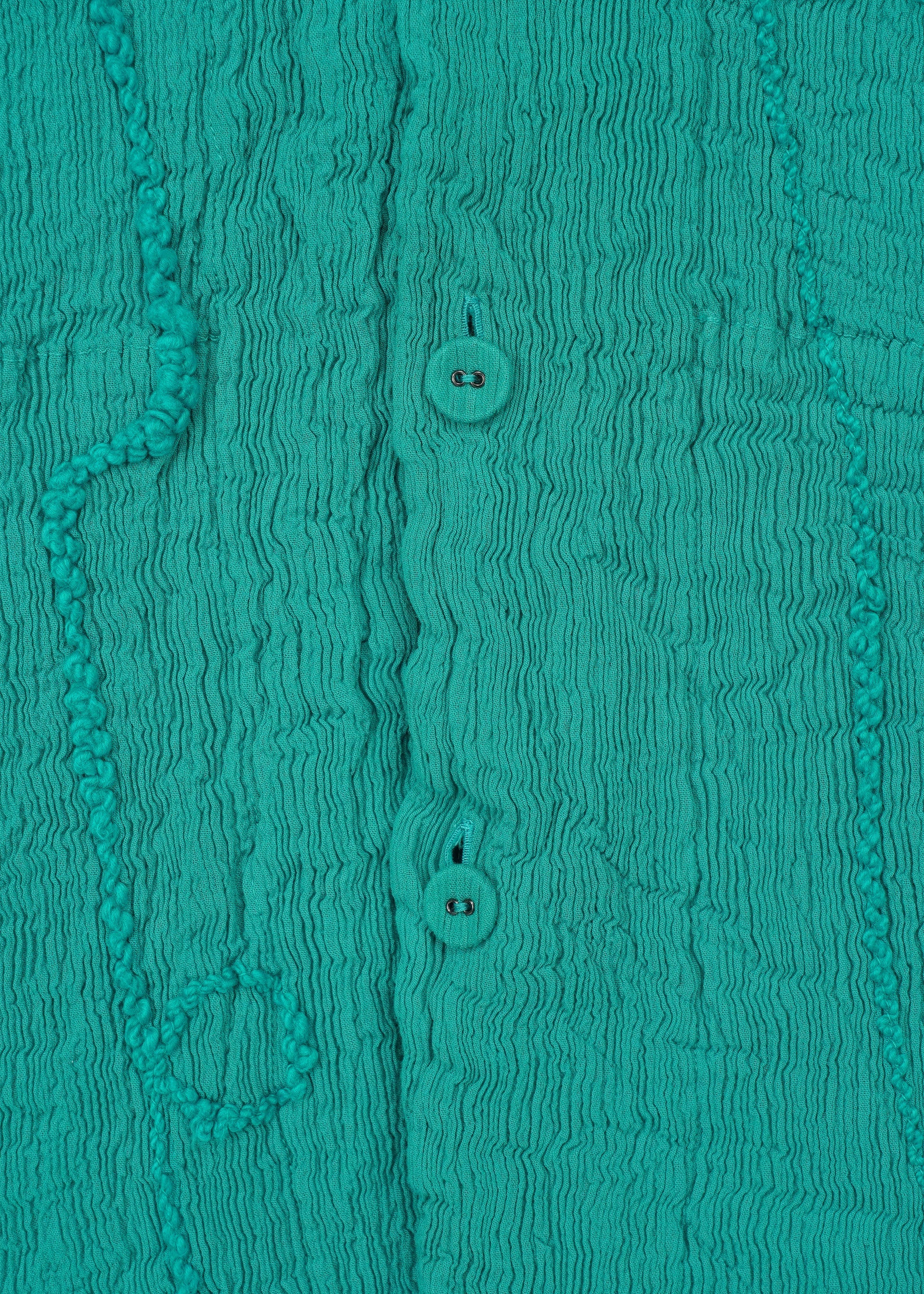 Zoomed view Close-up of teal KYO CHIJIMI EMB fabric by HaaT, showing vertical crinkles, two central round buttons, and irregular raised patterns for a soft, textured look.