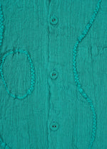 Close-up of HaaT's KYO CHIJIMI EMB jacket in teal, featuring vertical crinkles, three central buttons, and decorative raised stitched lines in wavy and oval embroidery-like patterns.