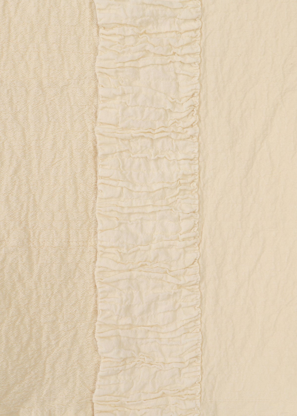 Close-up of HaaT's TENMOKU COTTON shows cream-colored garment-dyed fabric with a central vertical ruffle, flanked by two differently textured plain sections in matching off-white shades for subtle dimension. view 5 of 9