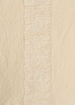 Close-up of HaaT's TENMOKU COTTON shows cream-colored garment-dyed fabric with a central vertical ruffle, flanked by two differently textured plain sections in matching off-white shades for subtle dimension.