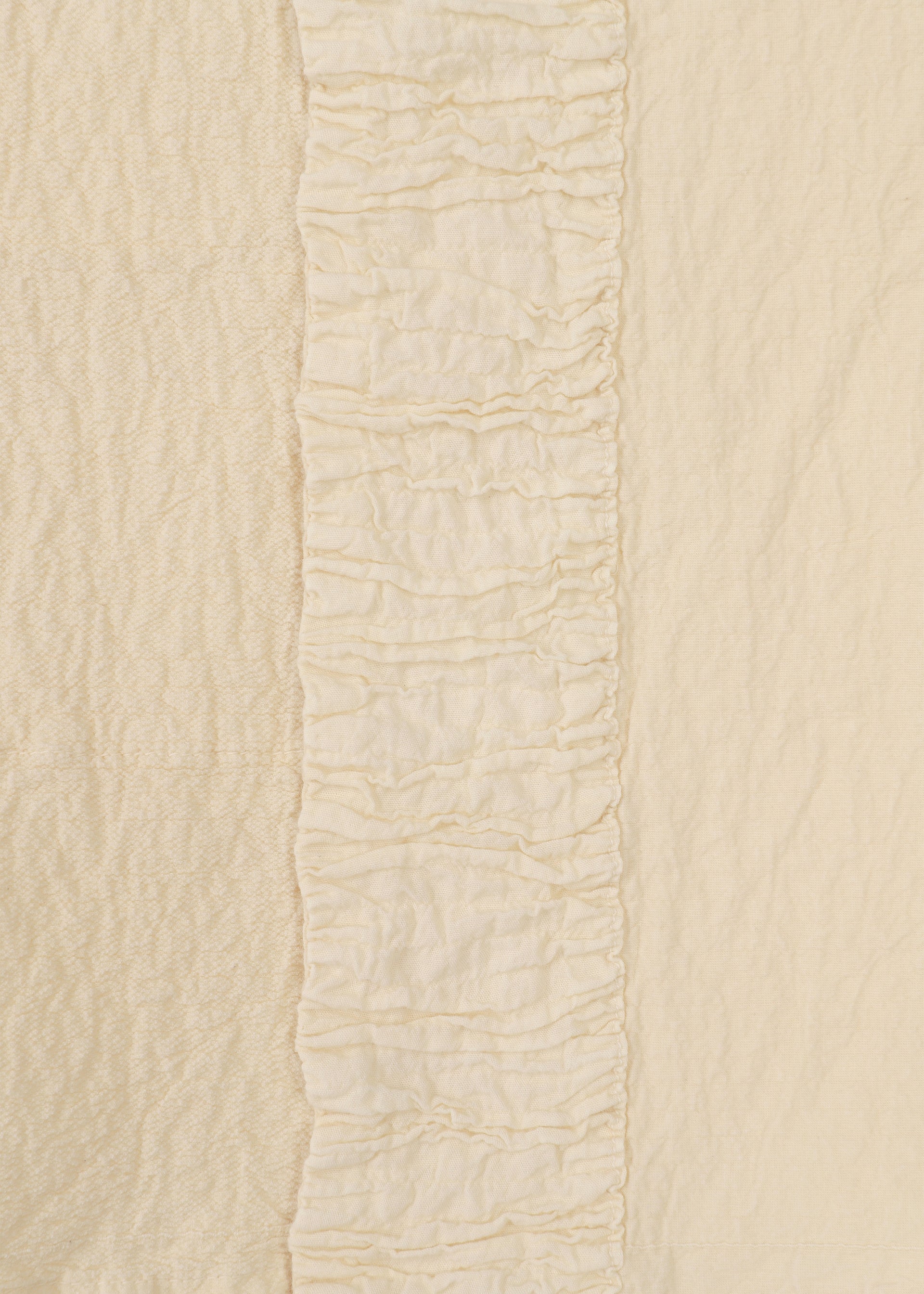 Zoomed view Close-up of HaaT's TENMOKU COTTON shows cream-colored garment-dyed fabric with a central vertical ruffle, flanked by two differently textured plain sections in matching off-white shades for subtle dimension.