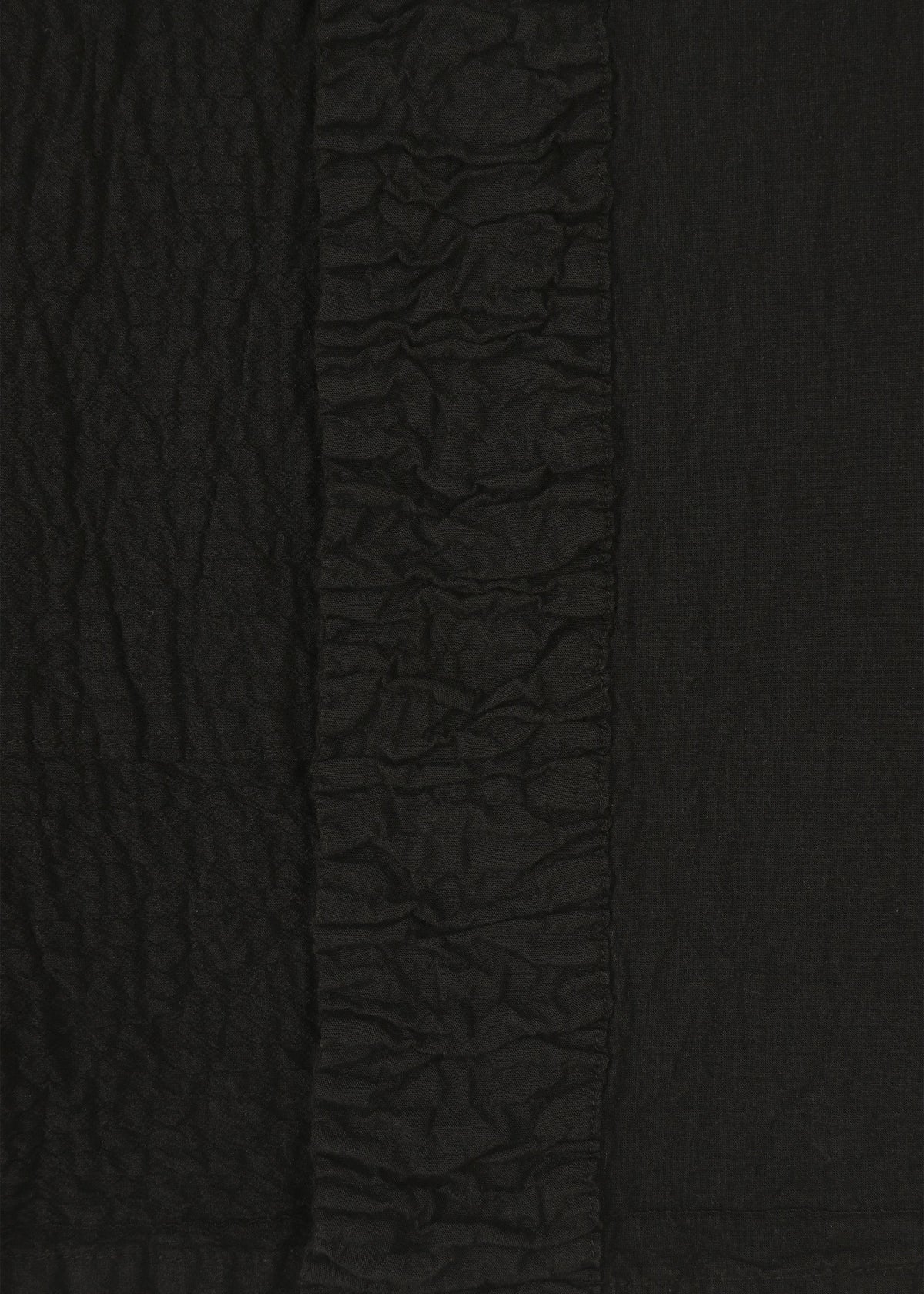 Close-up of black TENMOKU COTTON by HaaT, showing textured fabric with a crinkled pattern and a central vertical strip of tight ruching, echoing the intricate detailing of garment-dyed ceramics. view 4 of 7