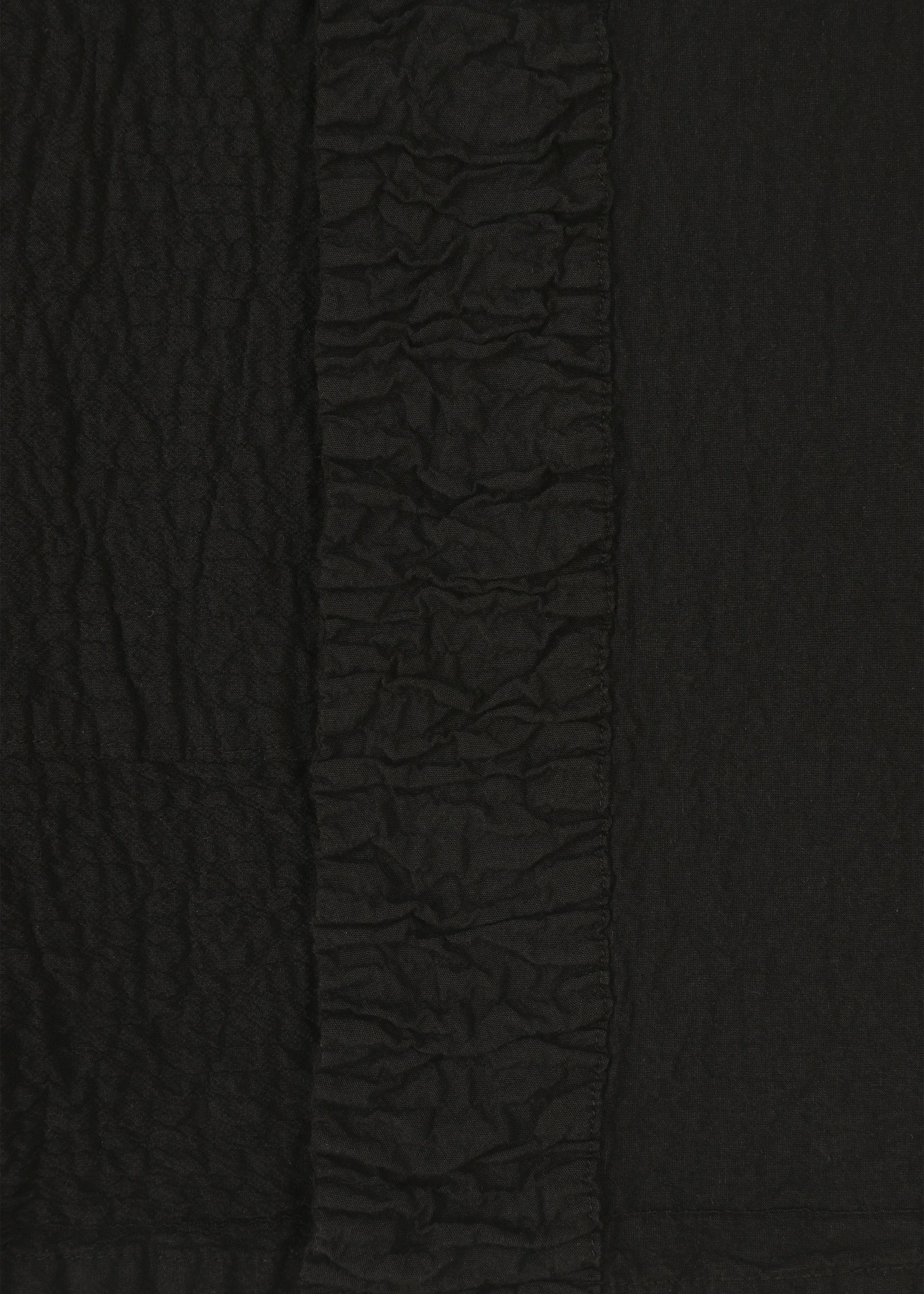 Zoomed view Close-up of black TENMOKU COTTON by HaaT, showing textured fabric with a crinkled pattern and a central vertical strip of tight ruching, echoing the intricate detailing of garment-dyed ceramics.
