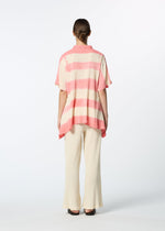 A person faces away against a white background, wearing a loose, short-sleeved pink and white striped shirt, cream HaaT KYO CHIJIMI ITAJIME pants made from ultra-fine cotton yarn on a unique loom, and black shoes.