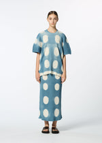 A person stands facing forward in a blue KYO CHIJIMI ITAJIME skirt and top by HaaT with large white oval polka dots, black slide sandals, and hair pulled back, against a plain white background.