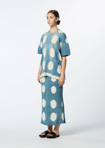 A woman wears the HaaT KYO CHIJIMI ITAJIME set—a matching light blue top and long skirt with large white polka dots—her hair pulled back, black sandals on, posing against a plain white background.